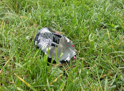 A piece of a can that has been cut by a grass mower