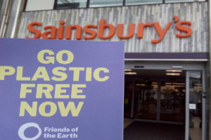 Sainsbury's logo with a Friend's of the Earth 'Go Plastic Free Now' leaflet in front of it