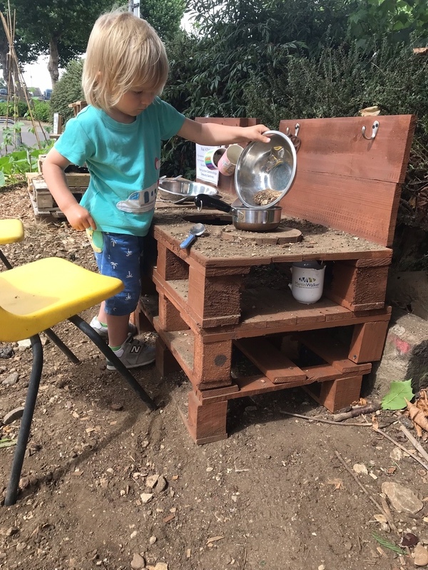 A child playing in the mud kitchen