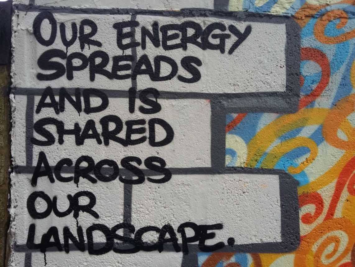 A section of painted cutaway bricks in the mural reads, 'Our energy spreads and is shared across our landscape'