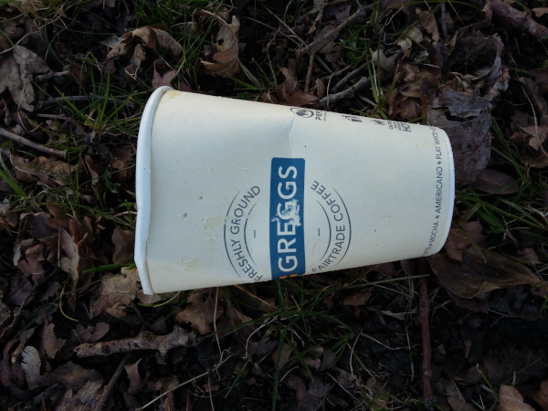 Greggs tea / coffee cup littered on an area of soil and leaves