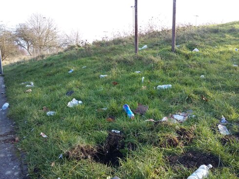 A lot of litter, especially plastic bottles, are strewn over a hillside