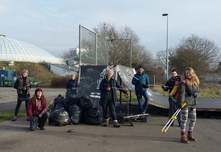 Group of litter pickers stand by a ramp in the skate park by a pile of collected rubbish.