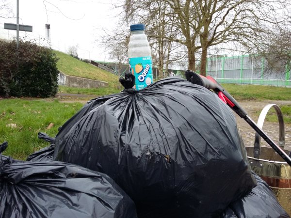 A pile of rubbish bags is topped by an empty plastic Oasis bottle