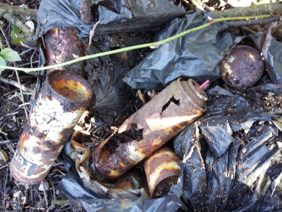 A dumped bag of rusted lighter fuel cans