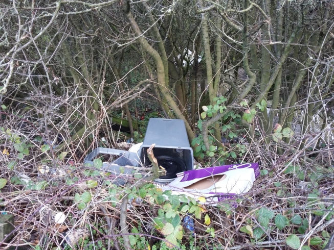 A dumped kitchen bin and other rubbish in woodland