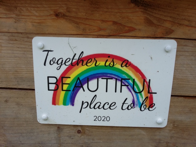Placard with a rainbow, reads, 'Together is a beautiful place to be. 2020.'