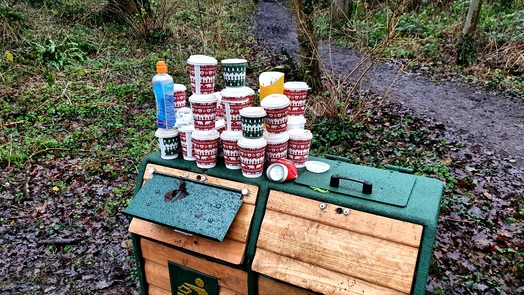 A haul of single-use coffee cups piled on a dual purpose bin