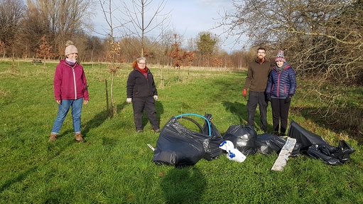 4 litter pickers stand by their rubbish haul in a field 