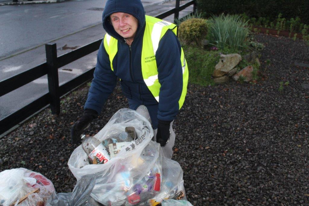 A litter picker smiles for the camera whilst tying up their bag