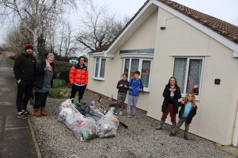 8 litter pickers stand in front of a house with their haul of rubbish bags