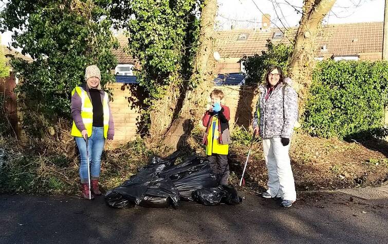 3 litter pickers stand on a path by their haul of rubbish