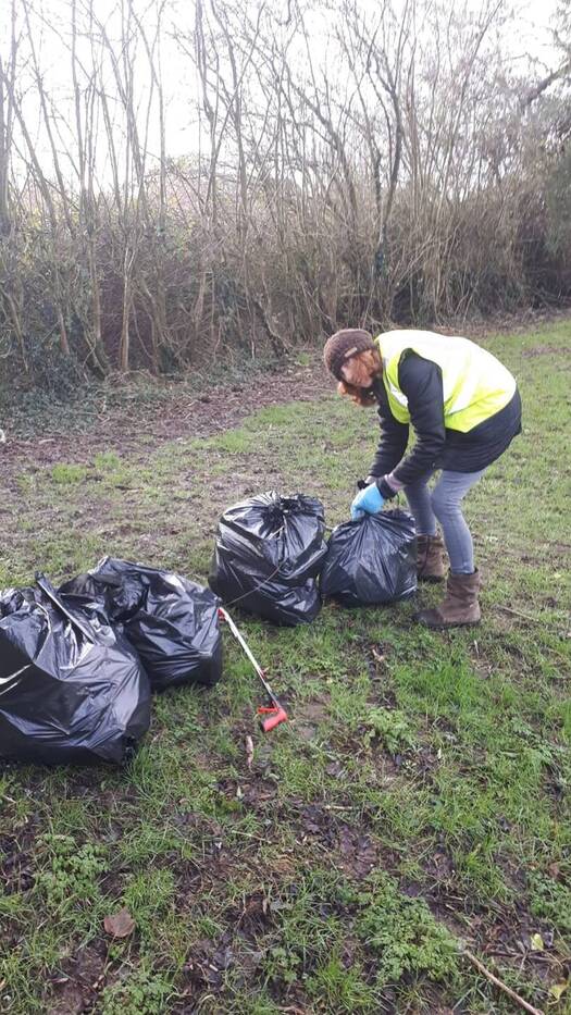A litter picker tying up one of several bags of collected rubbish