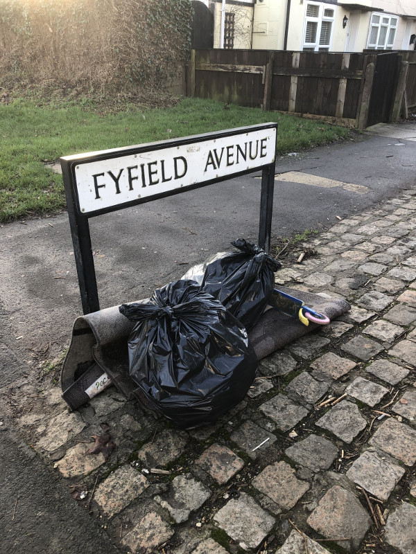 A collection of rubbish bags by the road sign for Fyfield Avenue