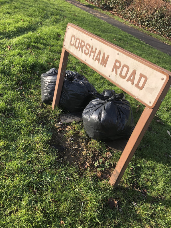 A collection of rubbish bags by the road sign for Corsham Road