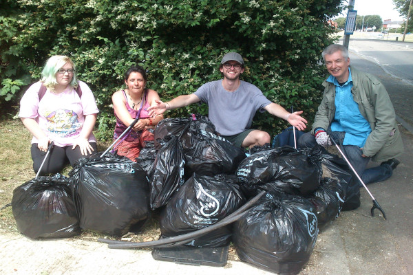 Litter pickers smile by the pile of collected rubbish