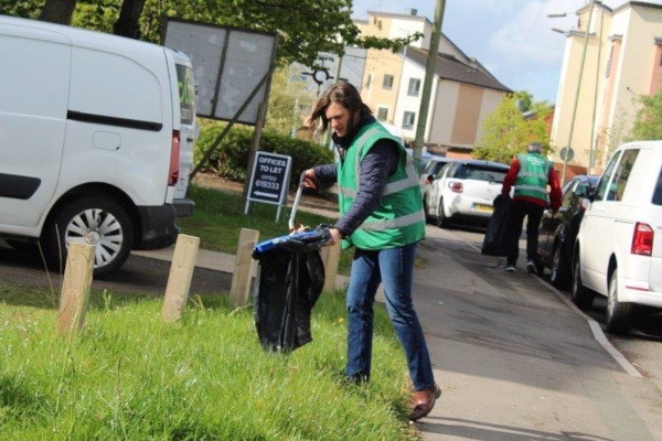 Litter pickers cleaning areas by parked cars