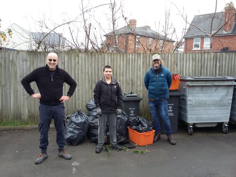 3 litter pickers pose for the camera with their hoard of litter by some bins