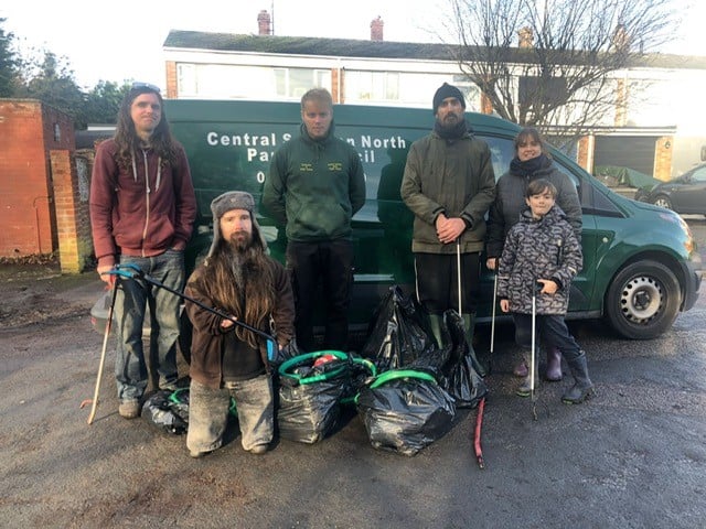 6 litter pickers stand by a Central North Swindon Parish Council van and bags of collected litter.