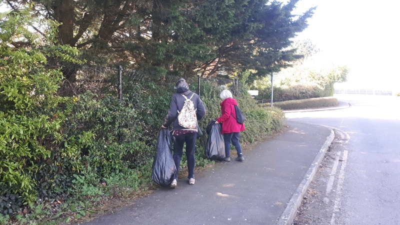 Litter pickers work in bushes close to Swindon New College