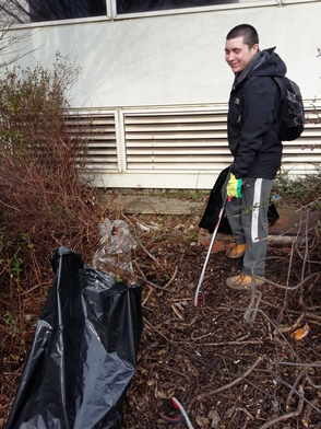 A litter picker by a building and bushes