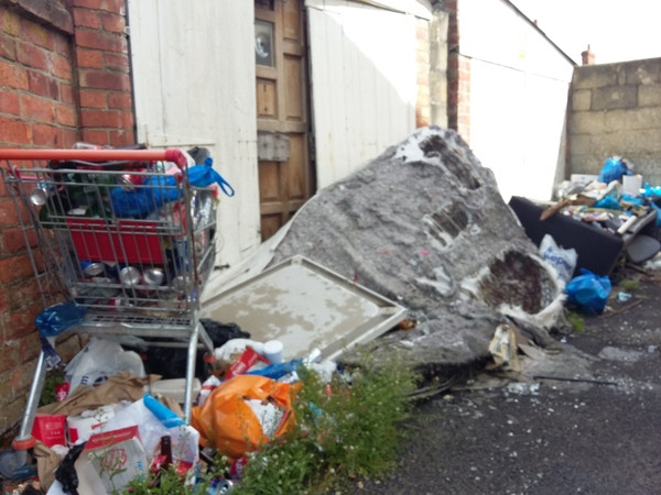 Flytipping in an alleyway includes a shopping trolley and mattress